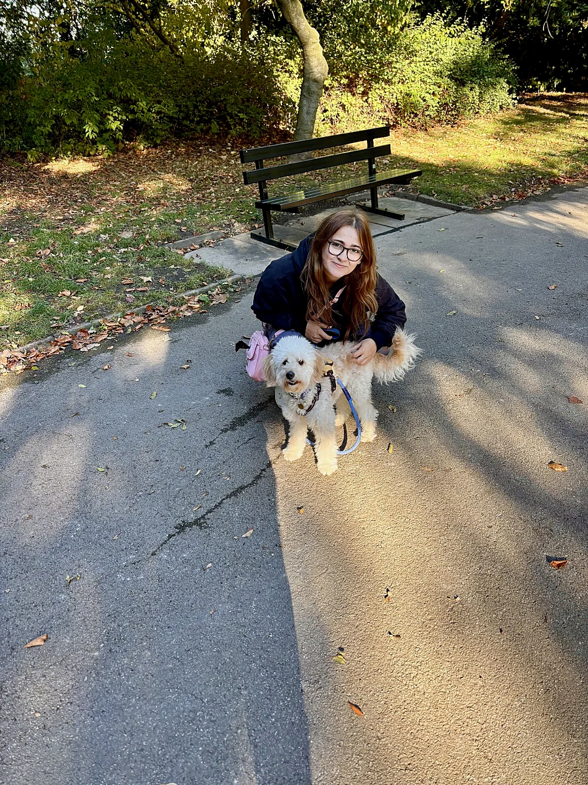 Ruby crouching beside a fluffy white dog outdoors