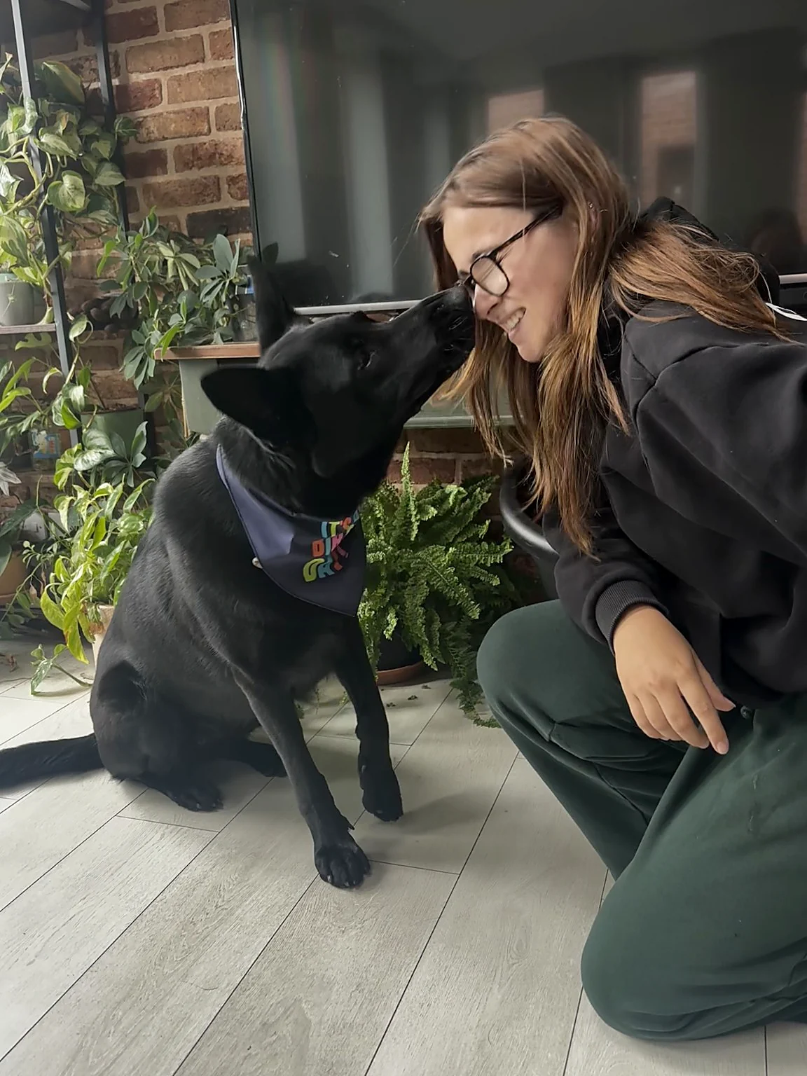 Ruby sharing an affectionate moment with a black dog